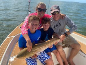 Family on boat holding large fish together